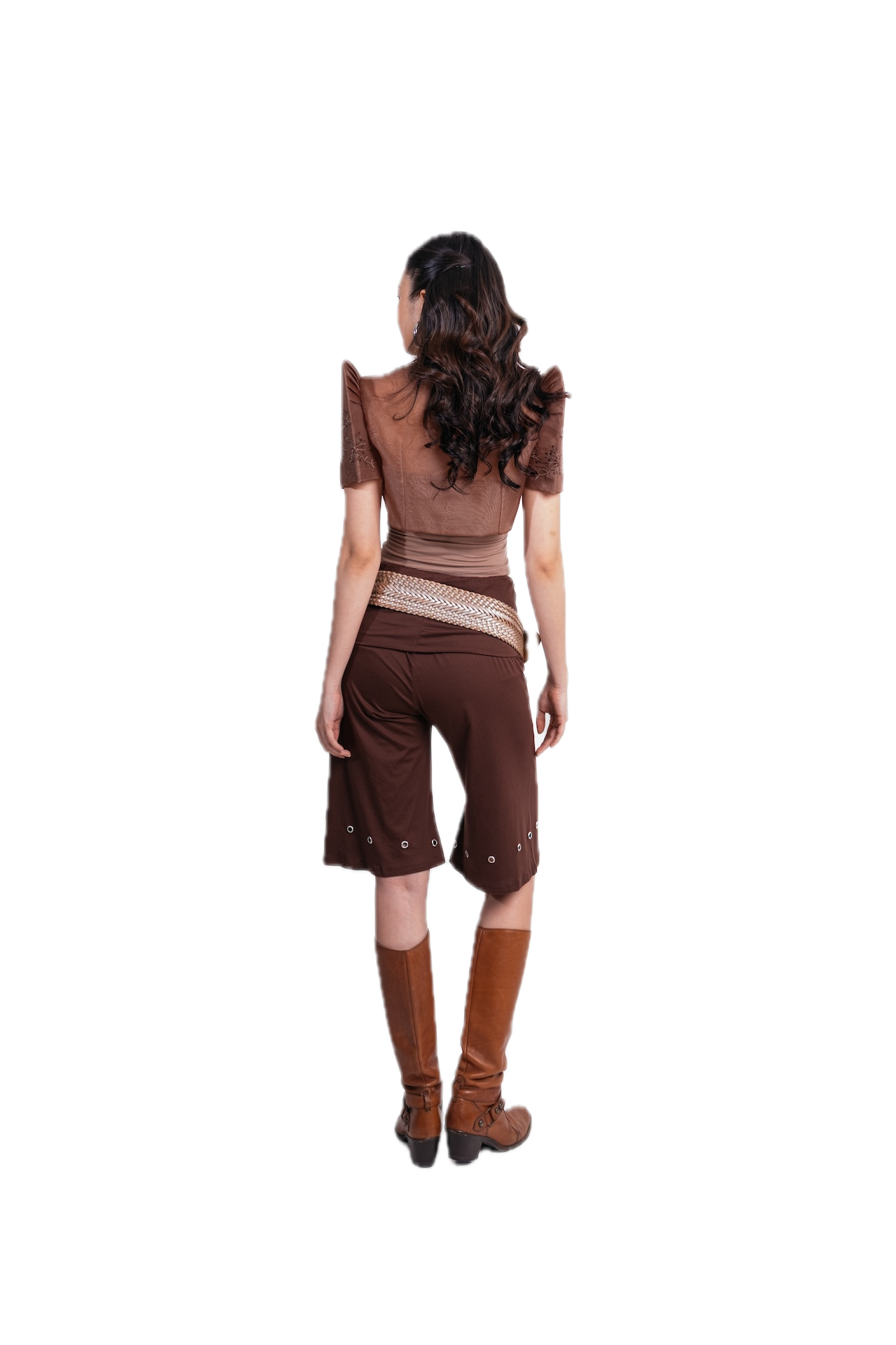 A woman shown from the back wearing a brown short-sleeve top with ruffled shoulders, matching brown shorts, a beige patterned waistband, and brown knee-high boots against a plain white background.