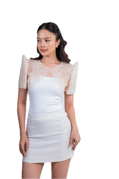 A woman modeling a white mini dress with sheer lace short sleeves and structured shoulders, photographed against a plain white background.